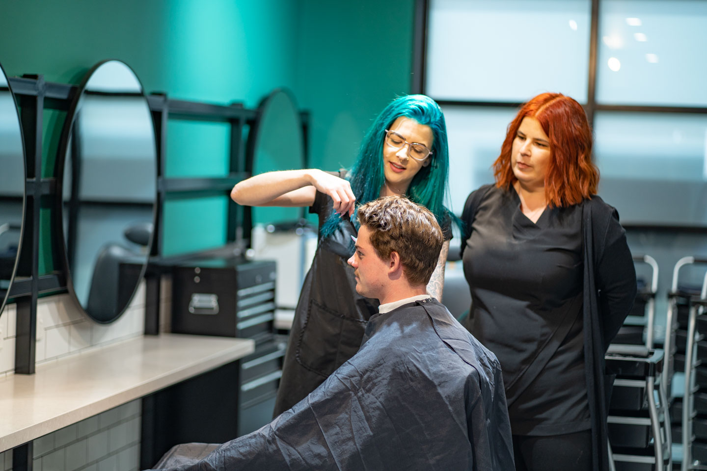 Teacher, student and client in a hairdressing salon training environment.