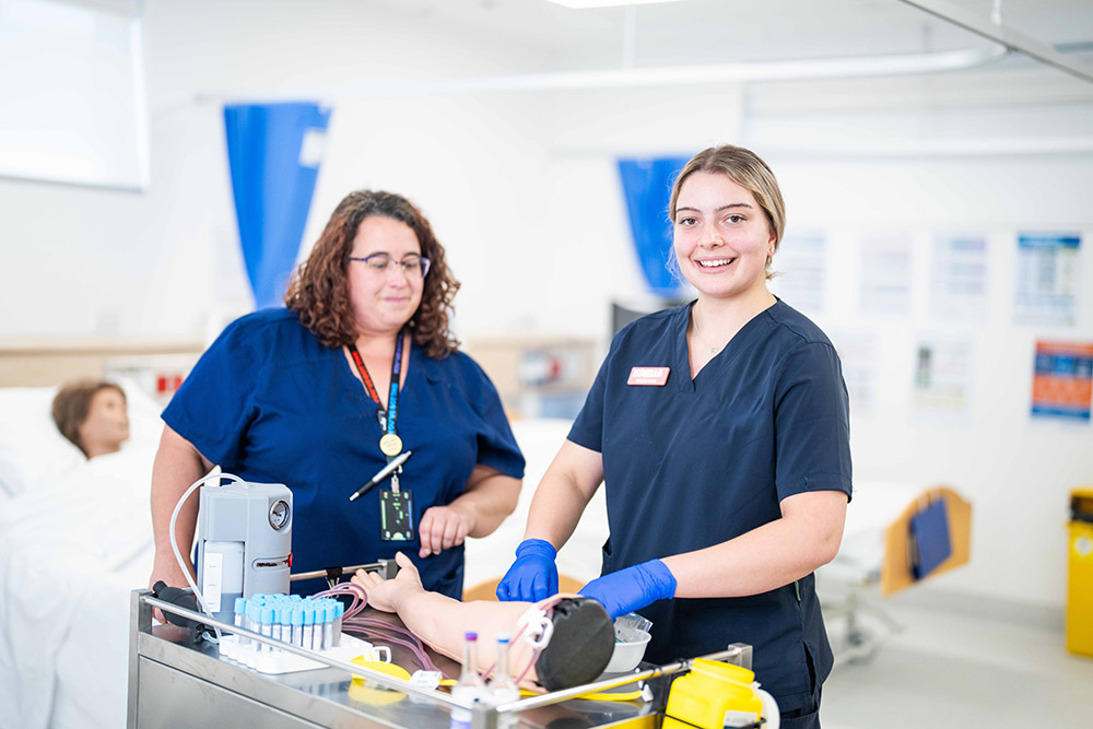 Young Female nursing student with a teacher overseeing hands-on practical learning